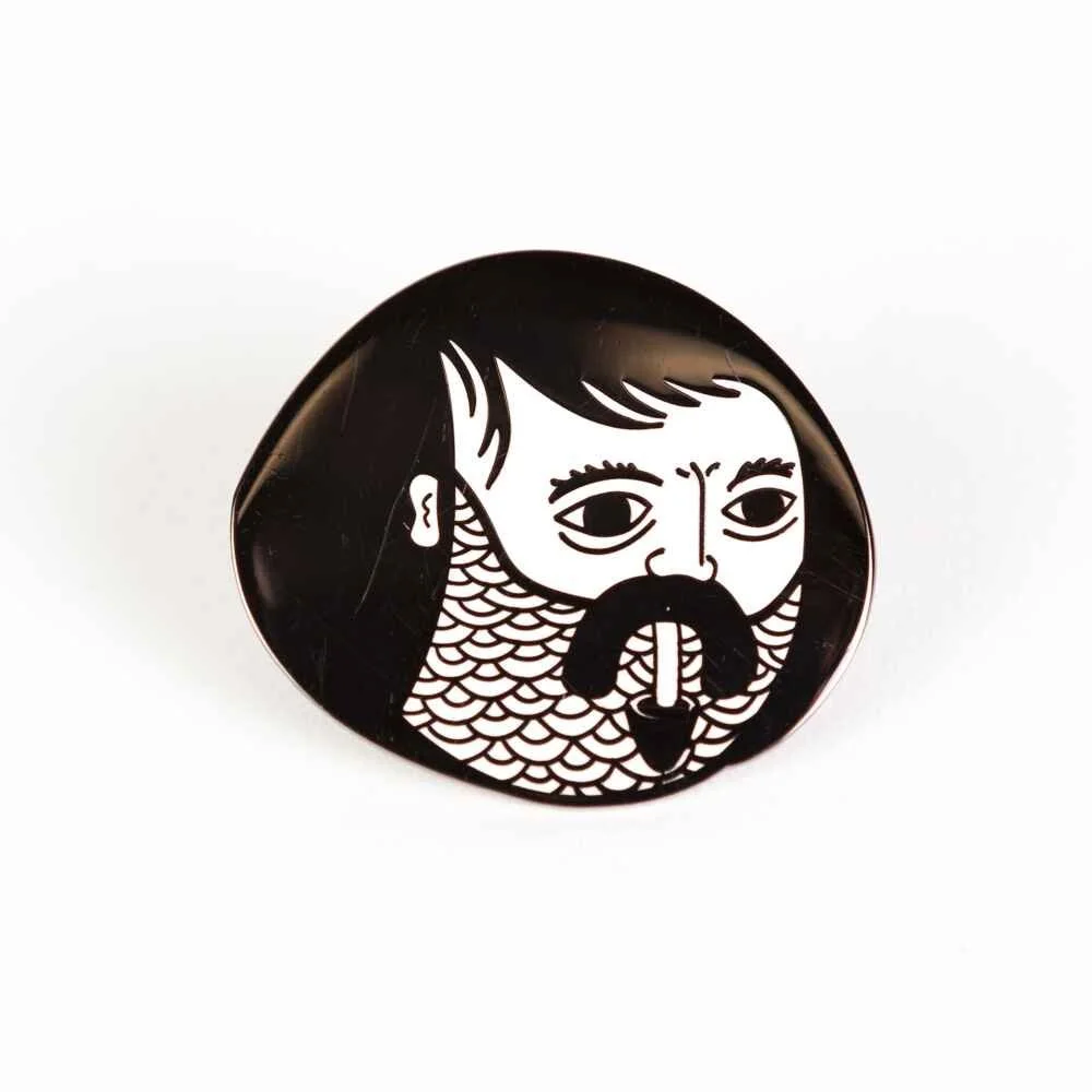 An oval hard enamel pin showing a bearded face in black and white.