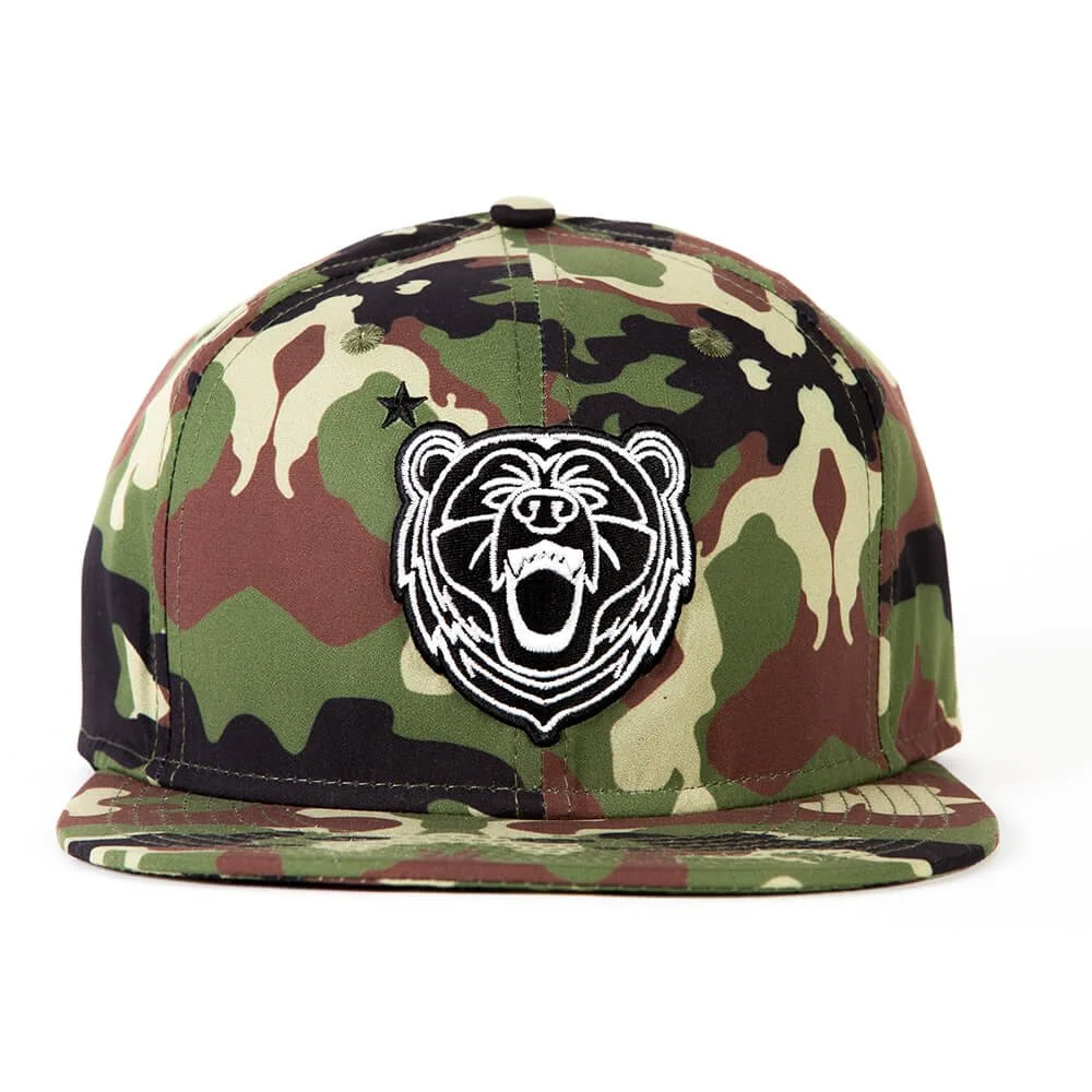 A camouflage snapback hat with an embroidered bear patch on the front.