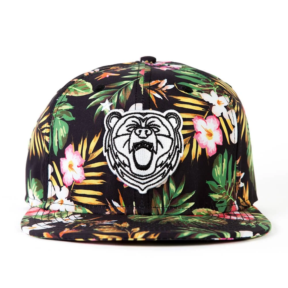 A snapback hat in a floral print with an embroidered bear patch on the front.