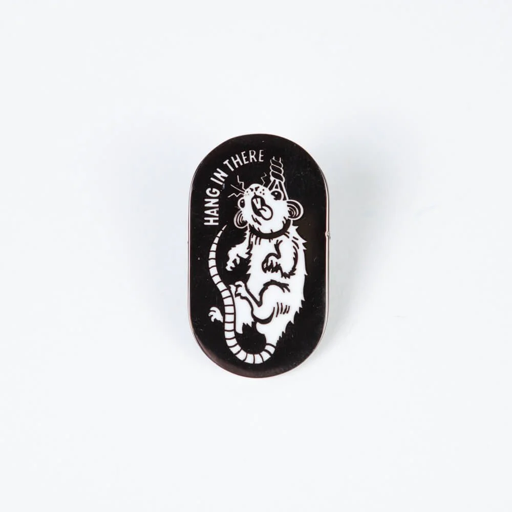 A black hard enamel pin with a white rat on it.