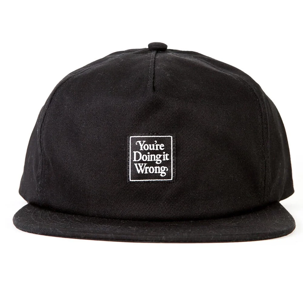 Black five panel cap with a small woven label stitched to the front panel.